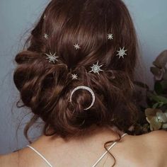 the back of a woman's head with stars and moon hair pins