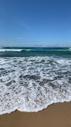 an ocean view with waves coming in to the shore and blue sky above, on a sunny day