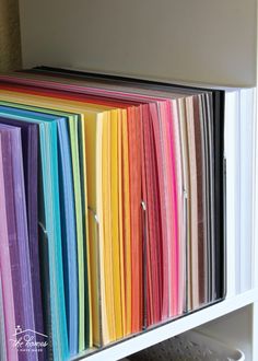 many different colored folders stacked on top of each other in front of a white cabinet