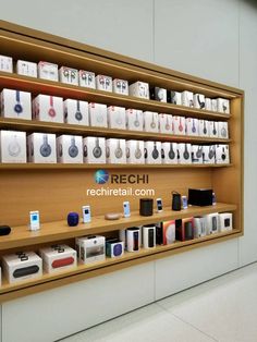 a display case filled with lots of electronic devices on shelves next to a white wall