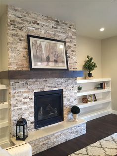 a living room with a fire place and bookshelves on the wall above it