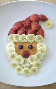 a white plate topped with fruit and a face made out of bananas