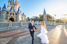 a bride and groom holding hands in front of a castle at disney's california adventure park