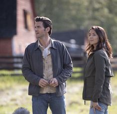 a man and woman standing next to each other in front of a dog on a leash