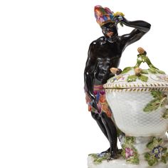 a black figurine sitting on top of a white vase