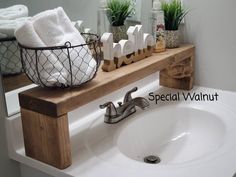 a white sink sitting under a bathroom mirror next to a wooden shelf filled with towels