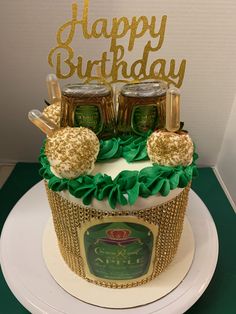 a birthday cake decorated with gold and green icing, topped with two beer cans