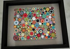 a black frame holds an art work made out of buttons