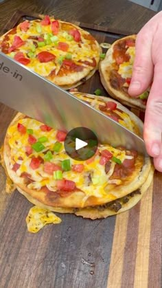 a person is cutting pizza with a large knife on a wooden board that has been cut into small pieces