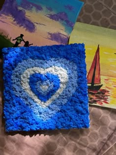 two paintings are shown on a bed and one has a blue square with a white heart