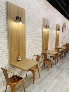 an empty restaurant with tables and chairs lined up against the wall, in front of a white brick wall