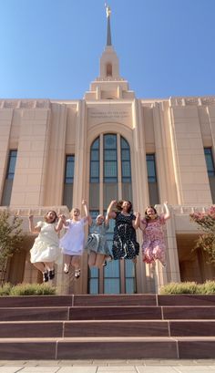 three women jumping in front of a church with their arms up and legs spread out