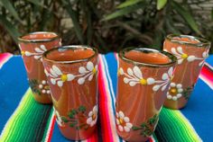 there are three glasses on the table with flowers painted on them and one is empty