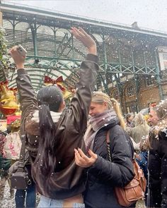 two people standing in the rain with their hands up