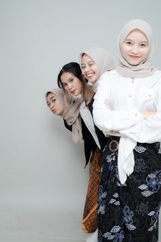 three women standing next to each other in front of a white wall with their arms crossed