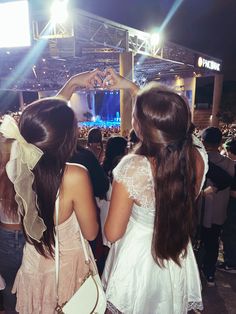 two girls standing in front of a crowd at a concert