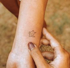 two hands holding each other with a small tattoo on their arm and wrist, both showing the outline of a turtle