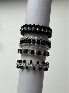 a stack of black and white beaded bracelets on a napkin holder with a clock in the background