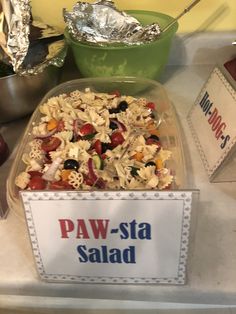 a bowl filled with pasta and vegetables next to a sign that says paw - sta salad