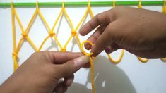 two hands are working on an orange string