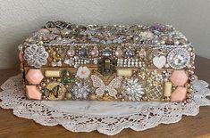 an old purse is covered with many different jewels and brooches on a lace doily