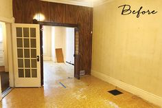 an empty room with wood paneling and the door to another room that is being renovated