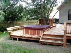 a hot tub sitting on top of a wooden deck next to a tree and fence