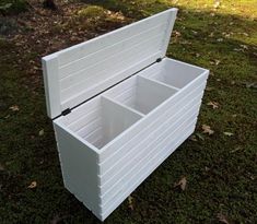 a white box sitting in the grass with two open compartments on each side and black handles at the top