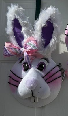 a close up of a stuffed animal head on a doorknob with pink and purple ribbons