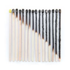 several matches are lined up in rows on a white surface, one is yellow and the other is black