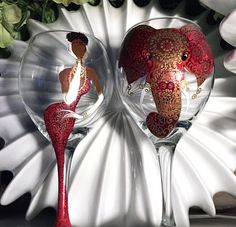 two wine glasses with designs on them sitting next to each other