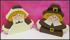 two paper dolls dressed in brown and white sitting next to each other on a pink background