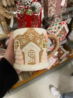 a person holding a coffee mug with a gingerbread house on it