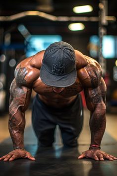 a man doing push ups on a gym floor with his hands behind his head and wearing a hat