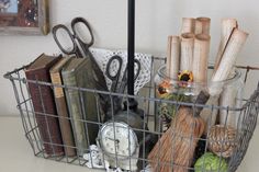 a metal basket filled with lots of books and knick - knacks on top of a table