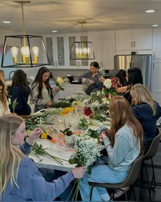 a group of women sitting around a table with flowers