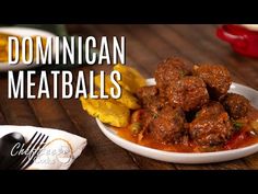 a white plate filled with meatballs and potatoes on top of a wooden table next to a fork