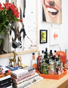 there are many books and liquor bottles on the table in front of this mirror,