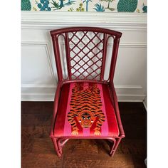 a red chair with a tiger painted on the seat and backrest, sitting in front of a fireplace