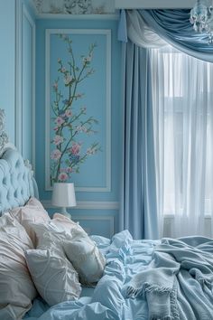 a bed with blue sheets and pillows in front of a painting on the wall behind it