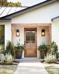 a white house with two large planters on the front porch and one door open