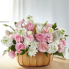 a basket filled with lots of pink and white flowers on top of a wooden table