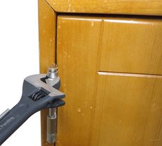 a wrench is attached to a wooden cabinet door