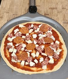 a pizza sitting on top of a pan covered in cheese and toppings with a spatula