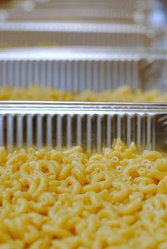 macaroni and cheese is being cooked in a pan on a conveyor belt