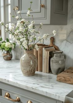 a vase with white flowers sitting on top of a counter next to books and other items