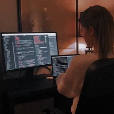 a woman sitting in front of a computer monitor with code on it's screen