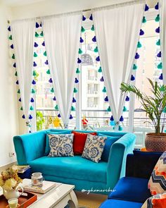 a living room filled with blue couches and colorful decorations on the windowsills