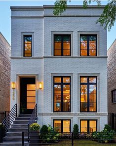 a white two story house with lots of windows and steps leading up to the front door