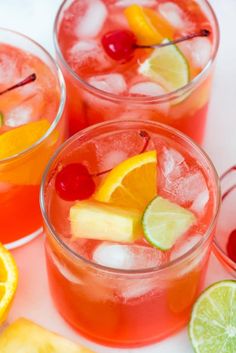 a person holding a glass with some fruit in it and ice cubes on the rim